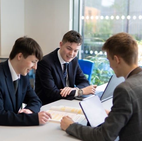 Students sitting at a desk working on laptops