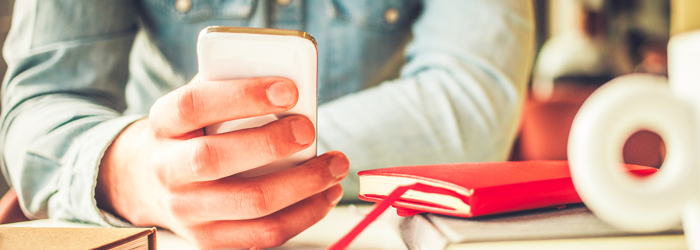 Person looking sitting at desk looking at mobile phone