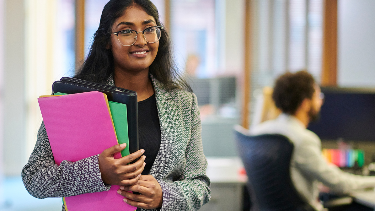 Industry_Marketing_Early_Careers_Case_Study_Leading_Tech_Firm A office worker pictured working through an office carrying notes
