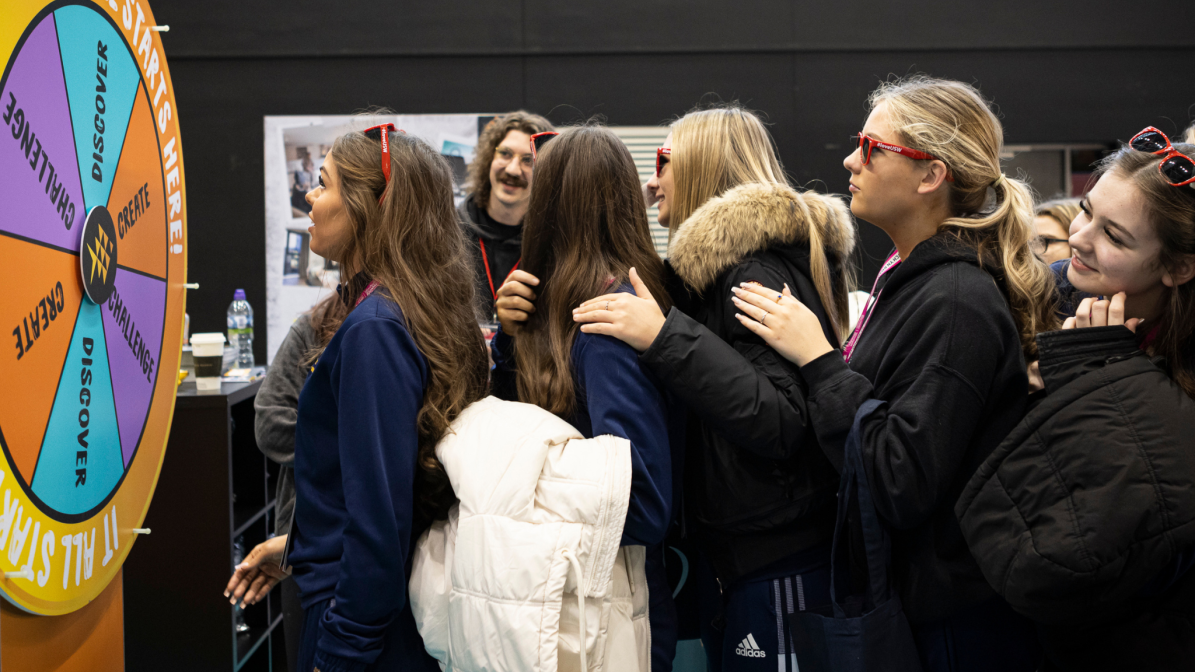 Students interacting with a spin-the-wheel game at a UCAS Discovery event