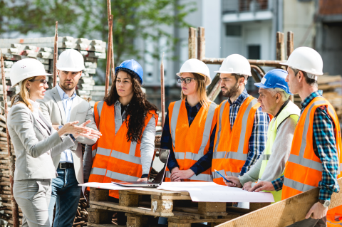 Industry_Marketing_Construction_Article_Text_Image_1_260324 A group of seven constructions workers, in hi vis jacket, stood around a project plan talking