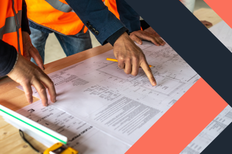 The hands of two construction workers examining blueprints